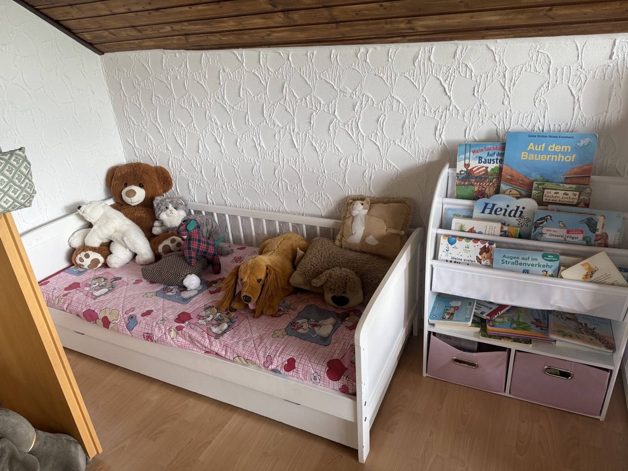 Kinderbett mit Kuscheltieren und Bücherregal